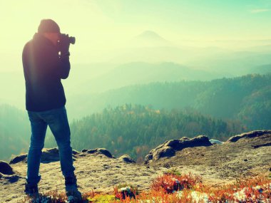 Cliff fotoğrafçı. Doğa fotoğrafçısı tepe üzerinde ayna kamera ile fotoğraf çeker