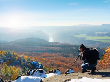 Profesyonel fotoğrafçı fotoğraf ayna kamera ve tripod ile karlı tepe üzerinde alır.