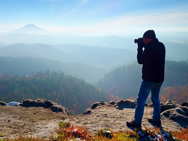 Fotógrafo profissional tira fotos com câmera de espelho no pico da rocha. Nevoeiro sonhador — Fotografia de Stock