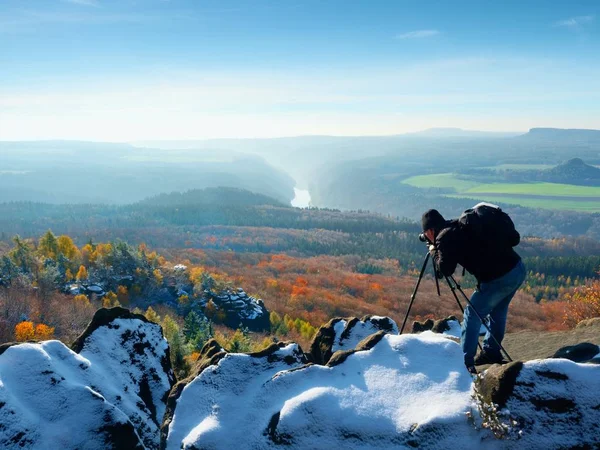 Профессиональный фотограф фотографирует с зеркальной камерой и штативом на снежной вершине — стоковое фото