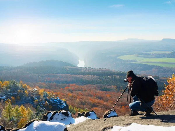 Fotógrafo profissional tira fotos com câmera de espelho e tripé no pico nevado — Fotografia de Stock