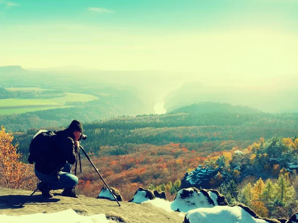 崖の上の専門家。自然写真家は、雪に覆われた岩の上のミラー カメラで写真をとります. — ストック写真