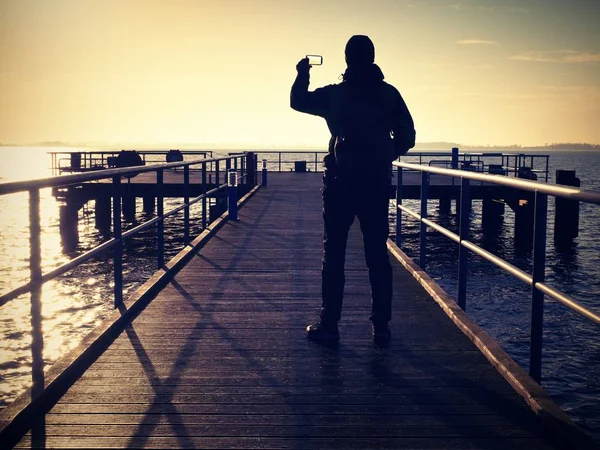 Hombre en el topo toma fotos de la mañana de primavera en el mar —  Fotos de Stock