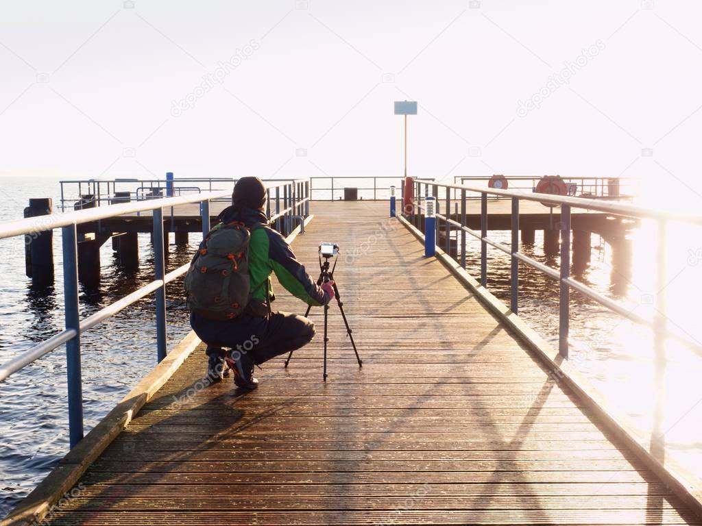 Alone artist on wooden bridge. Photographer with camera