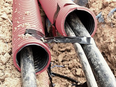 Koruyucu Hdpe boru içinde siyah kablolar ile hendek kazı. Metalik ve fiber optik kablo hatları.