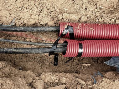 Koruyucu Hdpe boru içinde siyah kablolar ile hendek kazı. Metalik ve fiber optik kablo hatları.