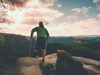 Ön kol koltuk değneği olan adam. Uzun yürüyüşe çıkan kimse zor yürüyüş sonra dağ tepe elde. Kırık bacak ile turizm