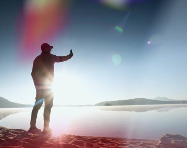 Kaçak ışık objektif. Uzun boylu ince adam egzersiz dağ gölü sahilde.