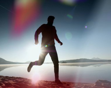 Kaçak ışık objektif. . Çalışan adam. Koş, sporcu adam kumlu bir plaj üzerinde gündoğumu sırasında koşu.