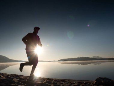 Güzel bir gün batımı fon karşı sahilde koşan adam. Kum dağ gölü