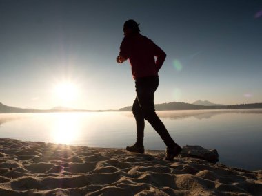 Güzel bir gün batımı fon karşı sahilde koşan adam. Kum dağ gölü