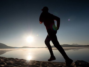 Güzel bir gün batımı fon karşı sahilde koşan adam. Kum dağ gölü