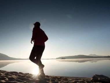 Güzel bir gün batımı fon karşı sahilde koşan adam. Kum dağ gölü