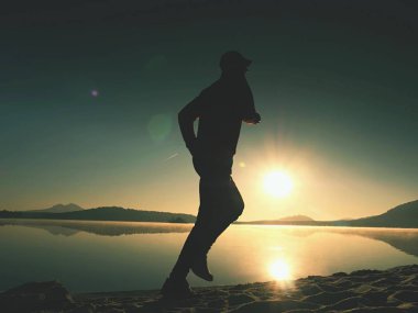 Güzel bir gün batımı fon karşı sahilde koşan adam. Kum dağ gölü