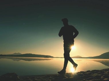 Güzel bir gün batımı fon karşı sahilde koşan adam. Kum dağ gölü