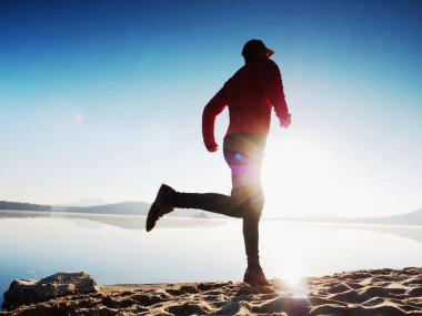 Güzel bir gün batımı fon karşı sahilde koşan adam. Kum dağ gölü