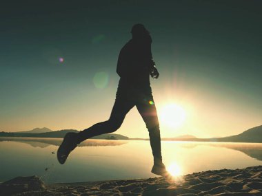 Güzel bir gün batımı fon karşı sahilde koşan adam. Kum dağ gölü