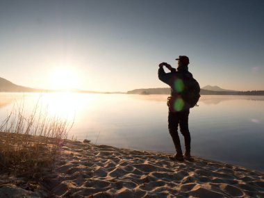 Onun arkasında da Denizi selfie fotoğraf çekmek için cep telefonu kullanarak deniz kenarında yalnız adam