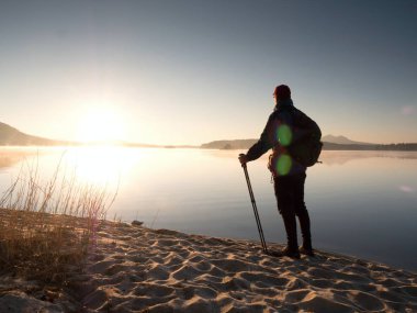 Kumsalda duran bir sırt çantası ve trekking Polonyalılar ile adam turist. Uzun yürüyüşe çıkan kimse keyfini çıkarın 