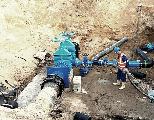 Trabajador subterráneo en válvula de compuerta, reconstrucción del sistema de agua potable — Foto de Stock