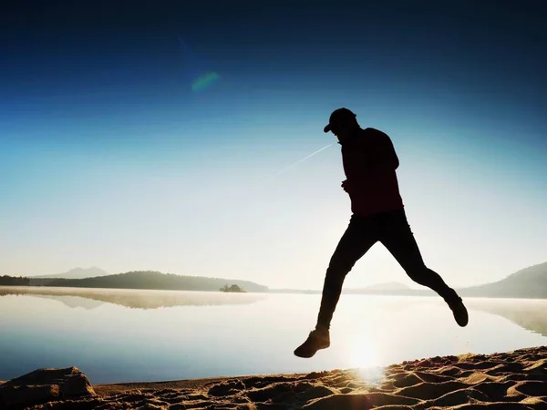 Muž běží na pláži nádherný západ slunce v pozadí. Písek z horské jezero — Stock fotografie