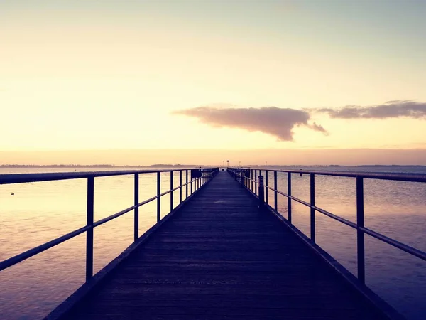 Ponte marítima de madeira vazia. A maneira de ver o nascer do sol acima do horizonte do mar — Fotografia de Stock