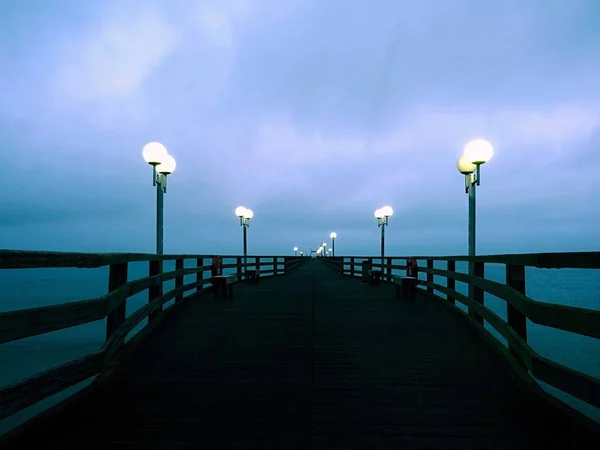 Φθινόπωρο σκοτεινή ομίχλη σε ξύλινη προβλήτα, πάνω στη θάλασσα. Κατάθλιψη, σκοτεινή ατμόσφαιρα. — Φωτογραφία Αρχείου