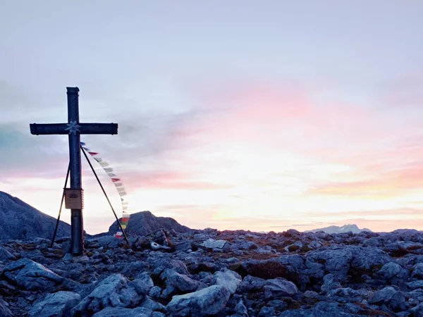 Big cross on top of  mountain as typical in the Alps. Wooden cross  with Buddhist praying flags — Stock Photo, Image