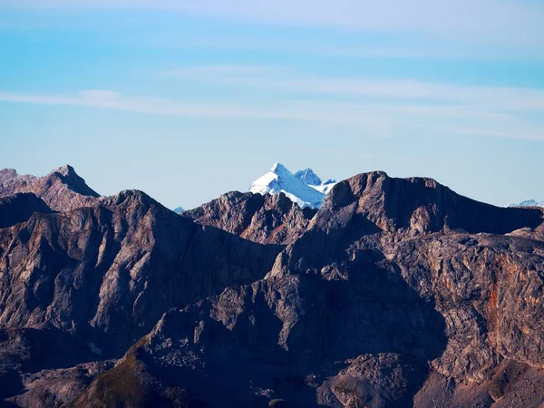 Rocky peak of Alps mountain in sunny day. Rock under fresh powder snow. — Stock Photo, Image