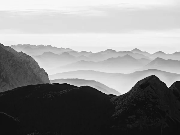 鋭い山のシルエット。遠い山脈とカラフルな霧の重い雲 — ストック写真