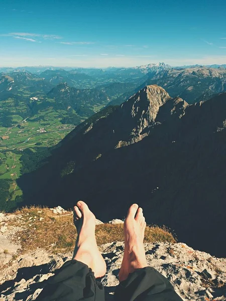 As pernas cruzadas descansam em trilha de montanha cansativa. Pernas masculinas suadas em calças trekking escuras relaxante — Fotografia de Stock