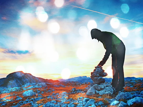 Filmkorneffekt. Allein erwachsener Mann stapelt Stein an Pyramide. Alpengipfel, — Stockfoto