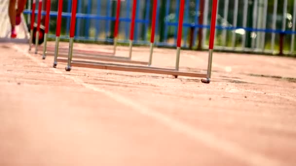 Спортивне тренування в спекотний літній день. Жінка-стартер стрибає через перешкоду на біговій доріжці . — стокове відео
