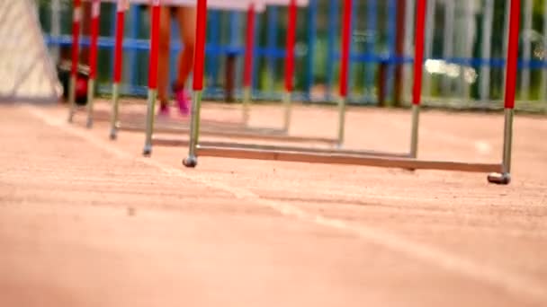 Sportlerin übt Hürdenlauf auf dem Sportplatz, hartes Athletiktraining an heißen Sommertagen — Stockvideo