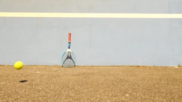 Court de tennis d'entraînement vide avec mur de tennis bleu rebondissant. Vieille boule jaune saute sur le pauvre sol asphalté — Video