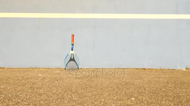 Palla da tennis rimbalzante contro il muro. Palla da tennis che salta sul campo, racchetta da tennis in alluminio molto vecchia appoggiata al muro . — Video Stock