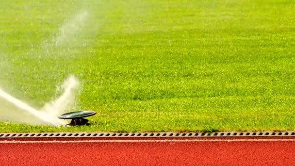 Bewässerungssystem für Fußball- oder Fußballplätze mit automatischer Rasenbewässerung. Bewässerung des Fußballplatzes, rote Gummibahnen im Freiluftstadion — Stockvideo