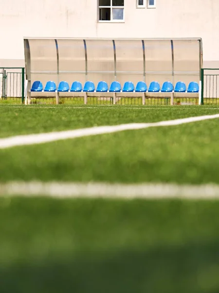 Nouveaux sièges en plastique bleu sur banc de joueurs de stade extérieur, chaises sous toit en plastique transparent — Photo