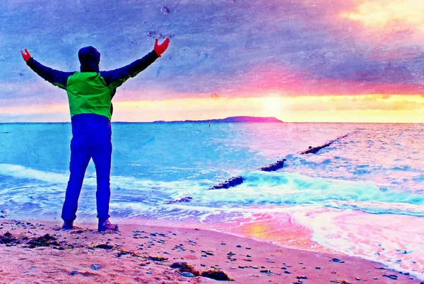 Filmové zrno. Silueta člověka samostatně na kamenitou pláž a sledují romantické barevné sunrise — Stock fotografie