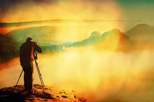 Cereale de film. Profesionist pe stâncă. Fotograful de natură face fotografii cu camera oglindă pe vârful stâncii. Dreamy fogy peisaj — Fotografie, imagine de stoc