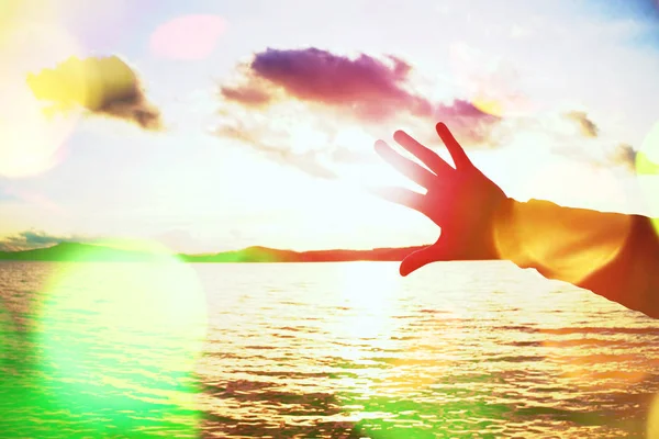 Grão de filme. Silhueta de mão e dedos tentar tocar o sol, pôr do sol acima do oceano — Fotografia de Stock