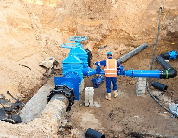 Worker underground for reconstrucion of drink water system. Technical expert at  gate valve