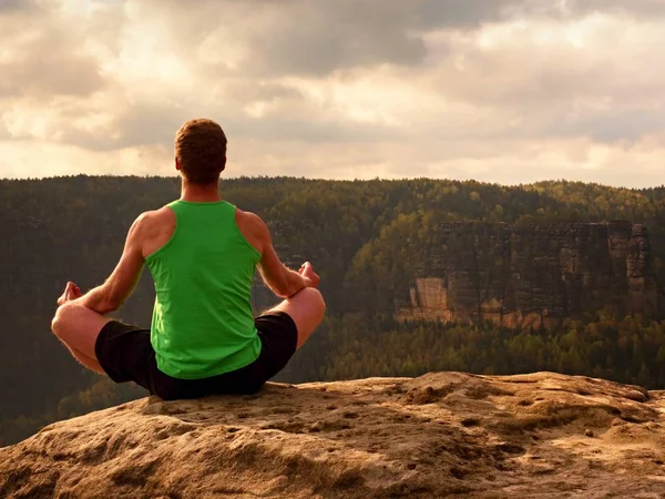 Adam içinde Lotus poz kayalık uçurum üzerinde meditasyon. Pratik Yoga taş kenarında sporcu 