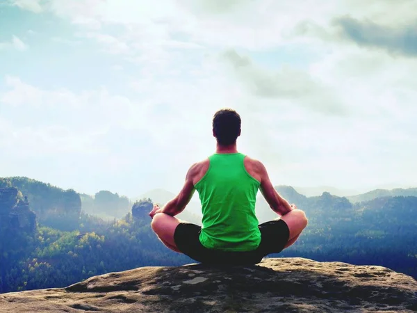 Man meditating in Lotus Pose on rocky cliff. Sportsman practicing Yoga on stone edge — Stock Photo, Image