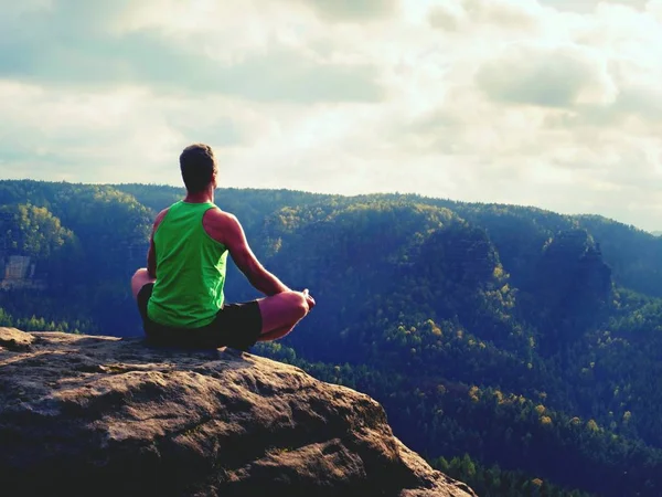 Solo el hombre está haciendo la postura del yoga en el pico de las rocas dentro de la mañana brumosa. Hombre de mediana edad practicando yoga —  Fotos de Stock