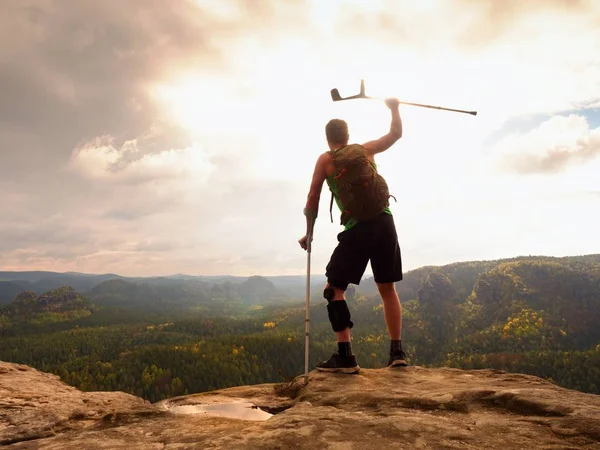 Doğada bir koltuk değneği olan adam. Kırık bacak koltuk değneği ile turist. Yaralı bacak bandaj ile seyahat