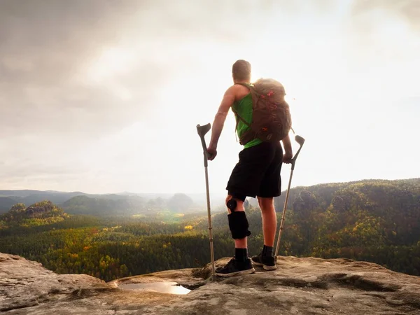 Adam bir koltuk değneği ile ve kırık bacak koltuk değneği üzerinde sabit. Gezgin bandaj yaralı bacak ile kal devam et