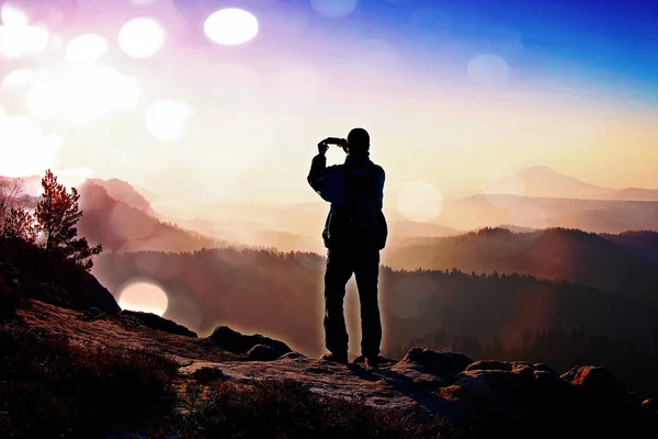 Film grain. Tourist takes photos with smart phone on peak of rock. Dreamy fogy landscape — Stock Photo, Image