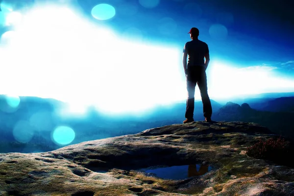 Пленка. Один турист в красной кепке стоит на вершине скалы из песчаника в парке рок-империй и наблюдает за туманной и туманной утренней долиной до Солнца. Ошибка природы — стоковое фото