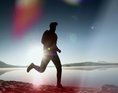 Kaçak ışık objektif. . Çalışan adam. Koş, sporcu adam kumlu bir plaj üzerinde gündoğumu sırasında koşu.